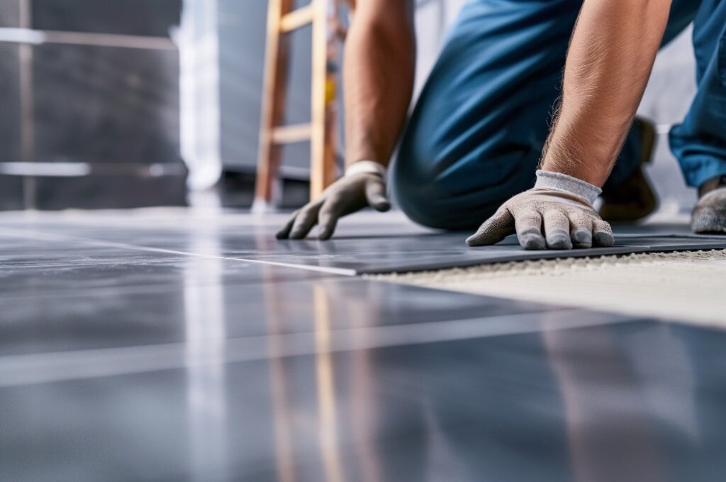 Fliesenleger verlegt Bodenplatten im Badezimmer